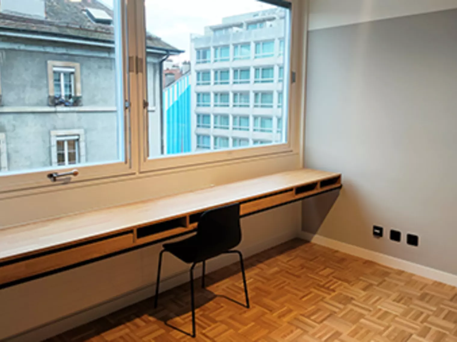 Un studio avec une console en bois, une chaise et une grande baie vitrée 