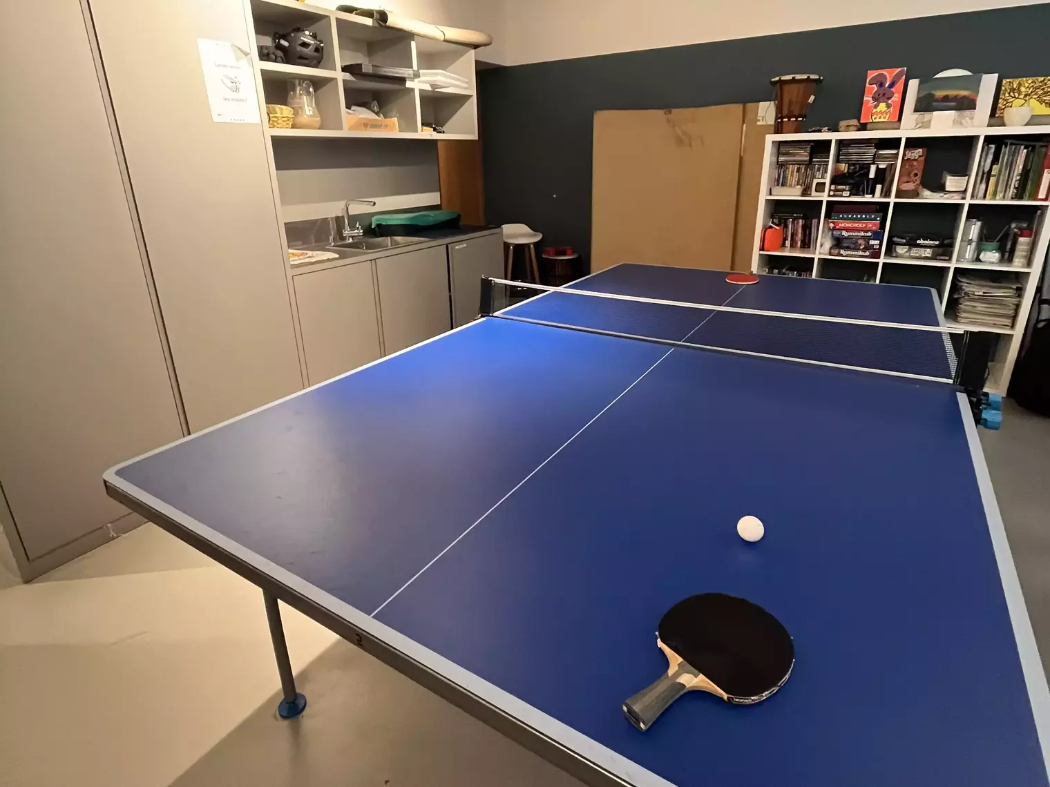 Une salle d'activités avec une bibliothèque et une table de ping-pong