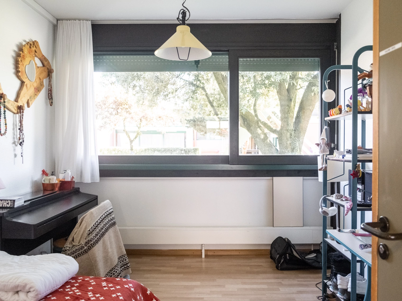 Une chambre avec une grande fenêtre, une bibliothèque et un bureau avec une chaise 