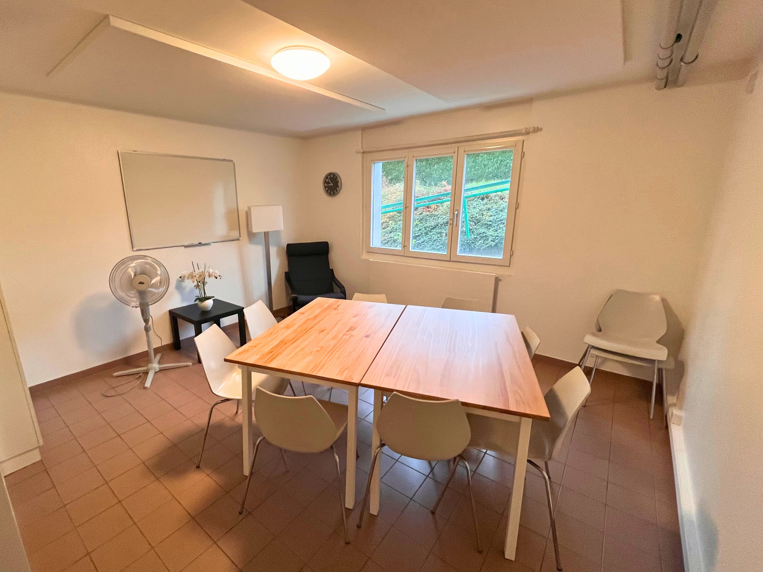 Une salle avec une table, des chaises et un tableau blanc au mur 