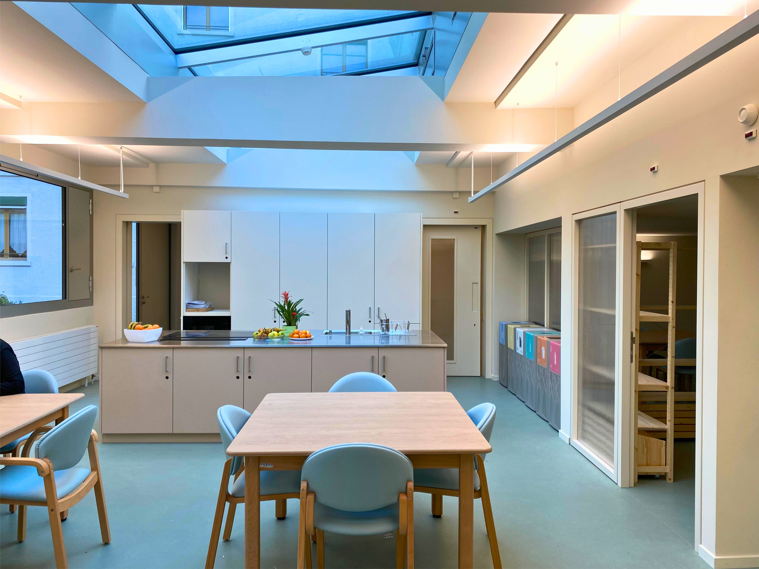 Une salle à manger avec des tables, des chaises et une cuisine moderne équipée